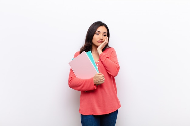 Young latin pretty woman  against flat wall with books