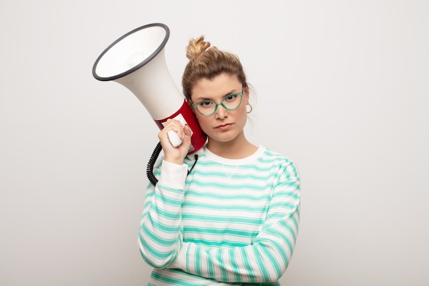 Young latin pretty woman  against flat wall with a megaphone