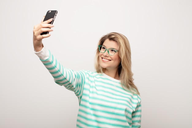 Young latin pretty woman  against flat wall with a smart telephone