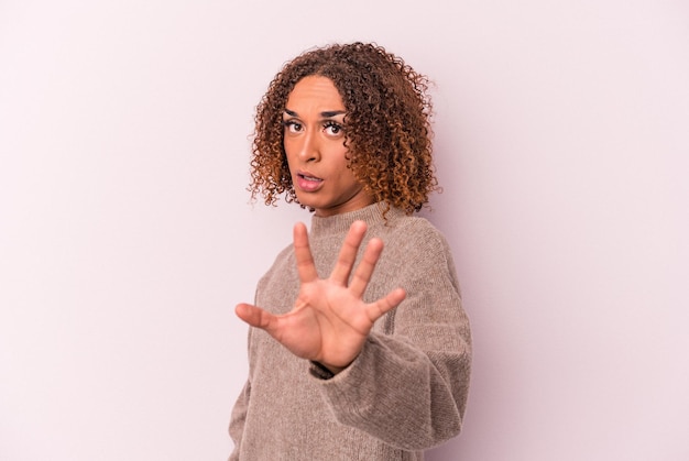 Young latin transsexual woman isolated on pink background being shocked due to an imminent danger