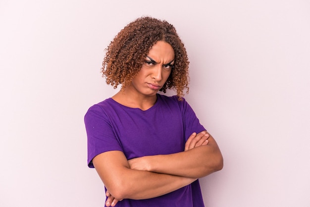 Young latin transsexual woman isolated on pink background frowning face in displeasure, keeps arms folded.