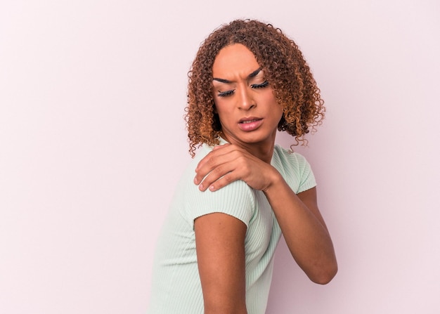 Young latin transsexual woman isolated on pink background having a shoulder pain.