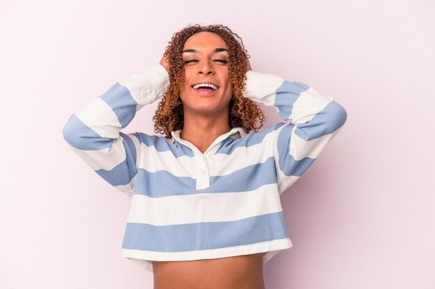 Young latin transsexual woman isolated on pink background laughs joyfully keeping hands on head. Happiness concept.