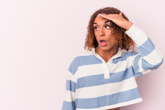 Young latin transsexual woman isolated on pink background looking far away keeping hand on forehead.