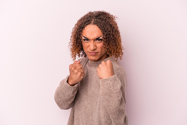 Young latin transsexual woman isolated on pink background showing fist to camera, aggressive facial expression.