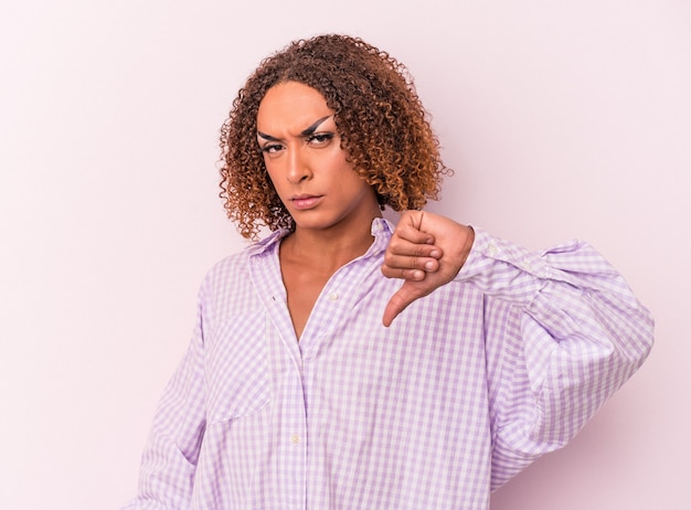 Young latin transsexual woman isolated on pink background showing thumb down, disappointment concept.