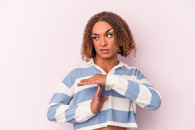 Photo young latin transsexual woman isolated on pink background showing a timeout gesture.