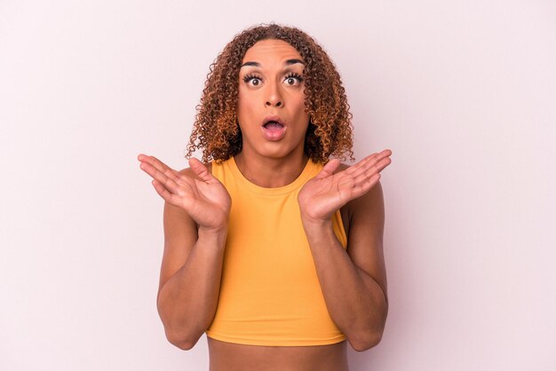 Young latin transsexual woman isolated on pink background surprised and shocked.