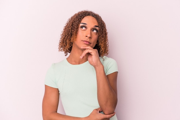 Photo young latin transsexual woman isolated on pink background thinking and looking up, being reflective, contemplating, having a fantasy.