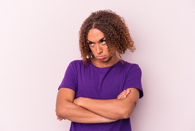 Young latin transsexual woman isolated on pink background tired of a repetitive task.