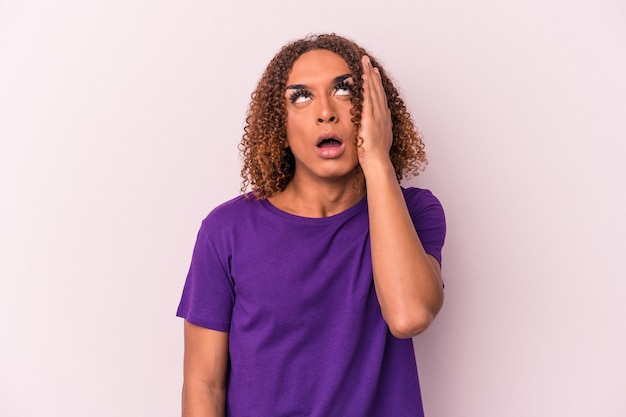 Young latin transsexual woman isolated on pink background tired and very sleepy keeping hand on head.