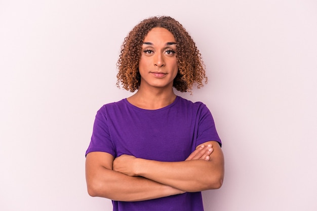 Young latin transsexual woman isolated on pink background who feels confident, crossing arms with determination.