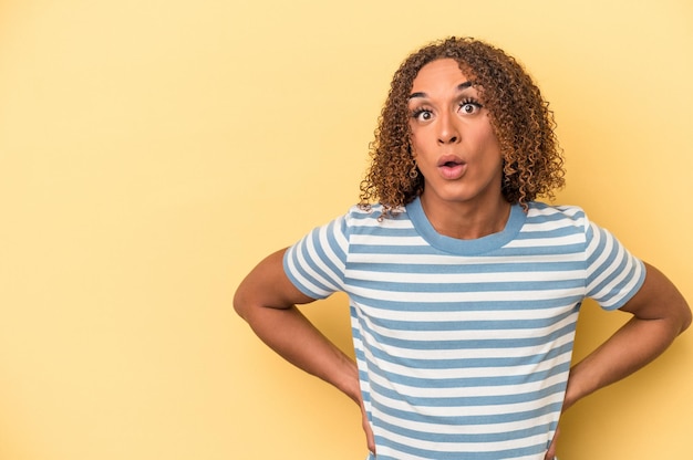 Young latin transsexual woman isolated on yellow background being shocked because of something she has seen.