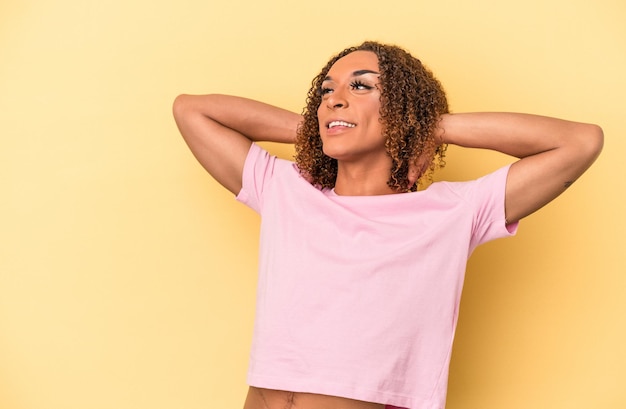 Young latin transsexual woman isolated on yellow background feeling confident, with hands behind the head.