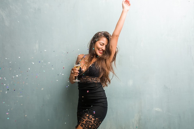 Young latin woman celebrating new year or an event. Excited and happy, holding a champagne bottle and a cup.