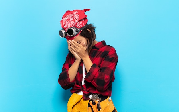 Young latin woman covering eyes with hands with a sad, frustrated look of despair, crying, side view