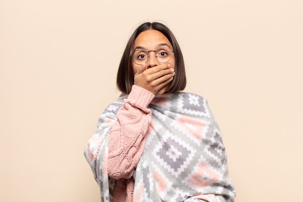 young latin woman covering mouth with hands with a shocked, surprised expression, keeping a secret or saying oops