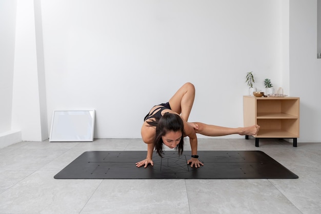 Молодая латиноамериканка, занимающаяся 8 углами, позирует в студии йоги в спортивной одежде и с местом для текста