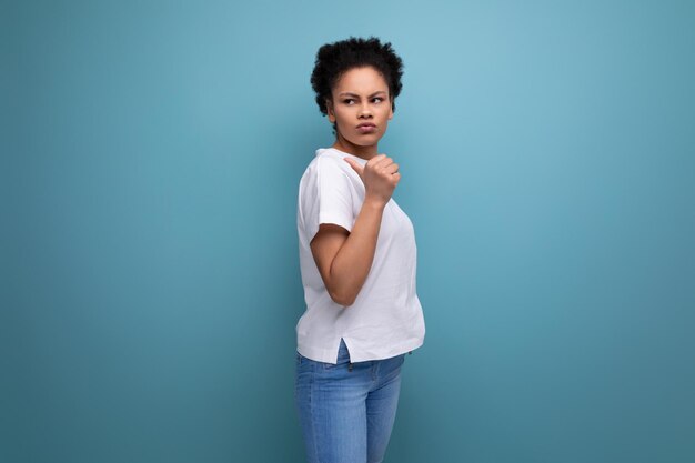 Photo young latin woman dressed in a white tank top with a mockup points her hand to the side