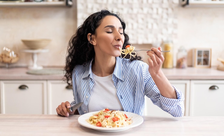 Photo young latin woman eating delicious pasta enjoying tasty homemade lunch with closed eyes while