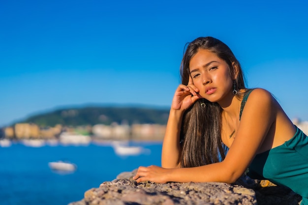 A young latin woman enjoying a green dress on summer vacations looking at the sea