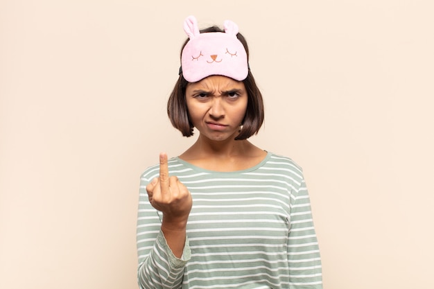 Young latin woman feeling angry, annoyed, rebellious and aggressive, flipping the middle finger, fighting back