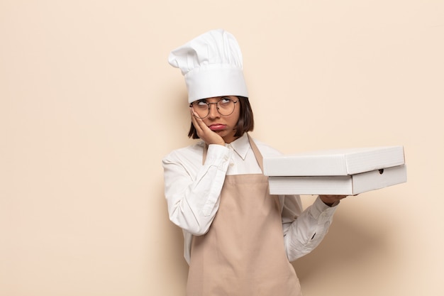 Photo young latin woman feeling bored, frustrated and sleepy after a tiresome, dull and tedious task, holding face with hand