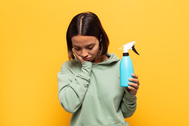 Young latin woman feeling bored, frustrated and sleepy after a tiresome, dull and tedious task, holding face with hand