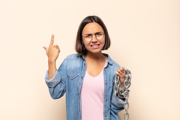 Young latin woman feeling confused and puzzled, showing you are insane, crazy or out of your mind