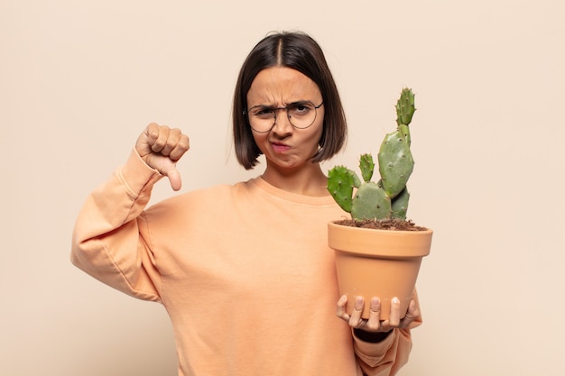 Photo young latin woman feeling cross, angry, annoyed, disappointed or displeased, showing thumbs down with a serious look