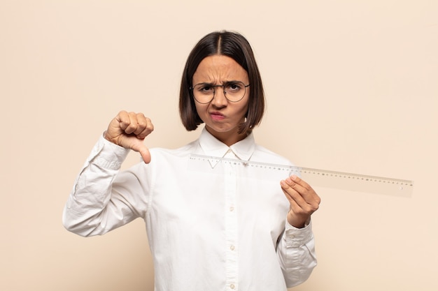 Young latin woman feeling cross, angry, annoyed, disappointed or displeased, showing thumbs down with a serious look