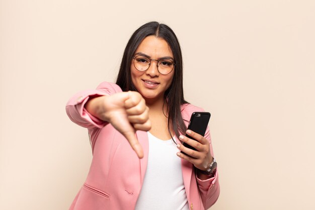 Young latin woman feeling cross, angry, annoyed, disappointed or displeased, showing thumbs down with a serious look