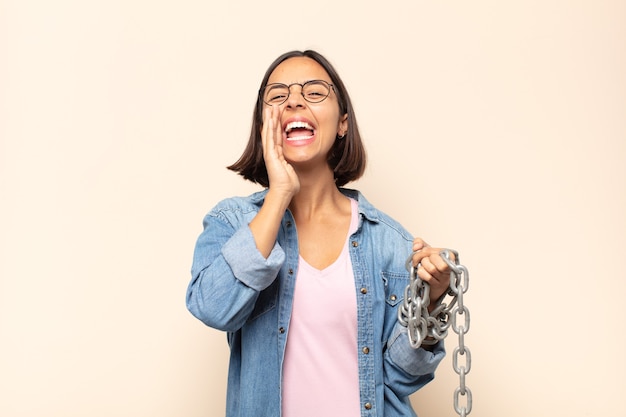 Giovane donna latina che si sente felice, eccitata e positiva, emette un grande grido con le mani vicino alla bocca, chiamando