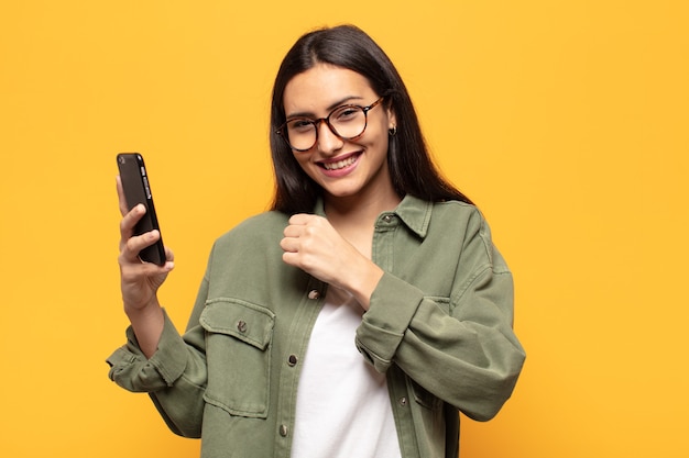 Young latin woman feeling happy, positive and successful, motivated when facing a challenge