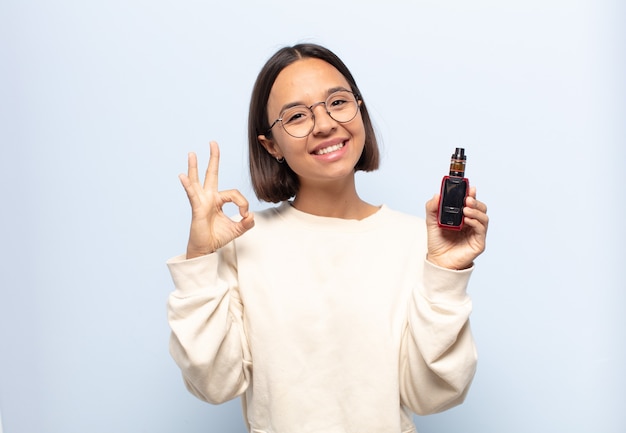 Young latin woman feeling happy, relaxed and satisfied, showing approval with okay gesture, smiling