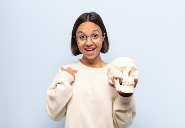 Young latin woman feeling happy, surprised and proud, pointing to self with an excited, amazed look