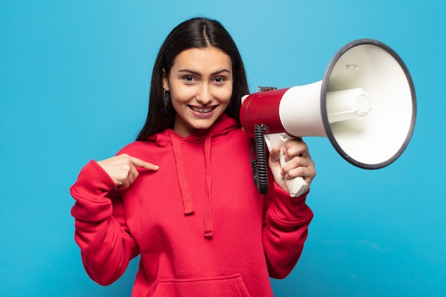 Young latin woman feeling happy, surprised and proud, pointing to self with an excited, amazed look