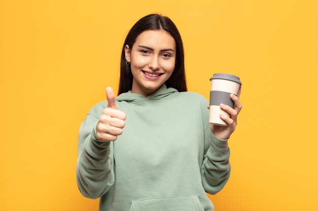 Young latin woman feeling proud, carefree, confident and happy, smiling positively with thumbs up