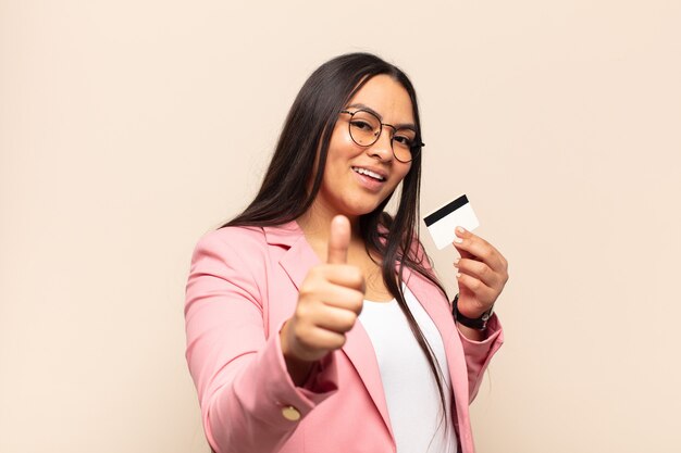 Young latin woman feeling proud, carefree, confident and happy, smiling positively with thumbs up