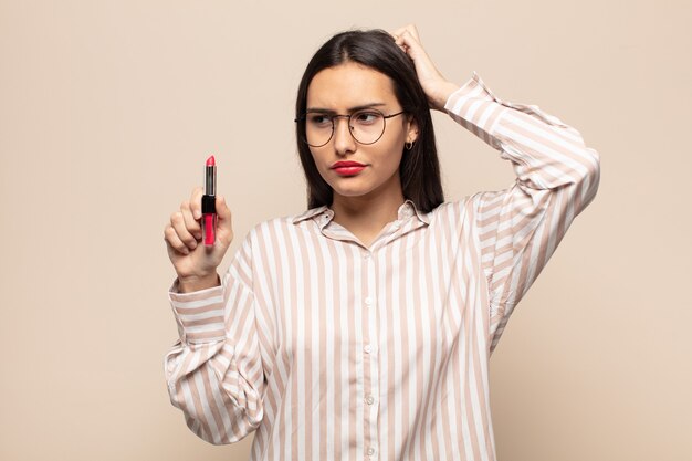 Young latin woman feeling puzzled and confused, scratching head and looking to the side