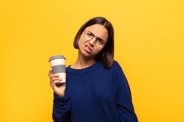 Young latin woman feeling puzzled and confused, with a dumb, stunned expression looking at something unexpected