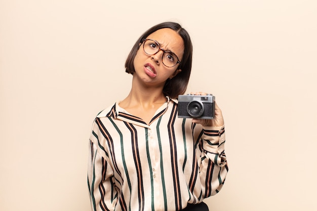 Young latin woman feeling puzzled and confused, with a dumb, stunned expression looking at something unexpected