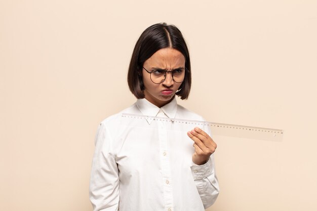 Young latin woman feeling sad, upset or angry and looking to the side with a negative attitude, frowning in disagreement