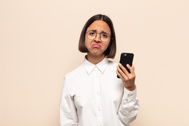 Young latin woman feeling sad and whiney with an unhappy look, crying with a negative and frustrated attitude