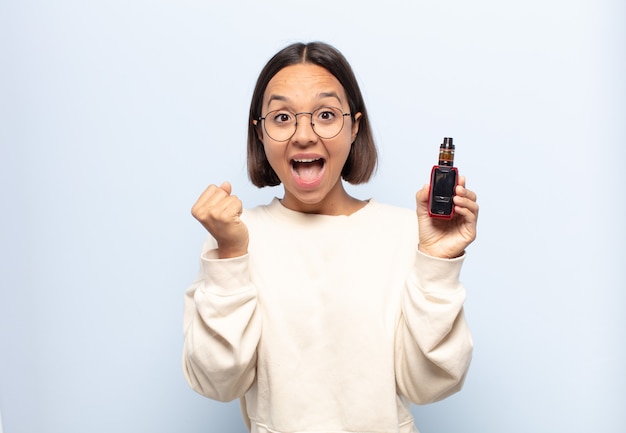 Young latin woman feeling shocked, excited and happy, laughing and celebrating success, saying wow!