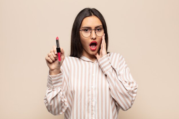 Young latin woman feeling shocked and scared, looking terrified with open mouth and hands on cheeks