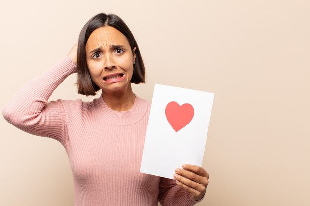 Young latin woman feeling stressed, worried, anxious or scared, with hands on head, panicking at mistake