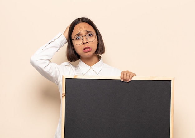 Young latin woman feeling stressed, worried, anxious or scared, with hands on head, panicking at mistake