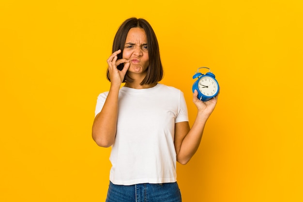 Young latin woman holding an alarm clock