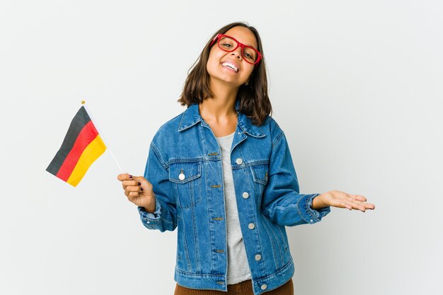 Young latin woman holding a german flag isolated on white background showing a welcome expression.